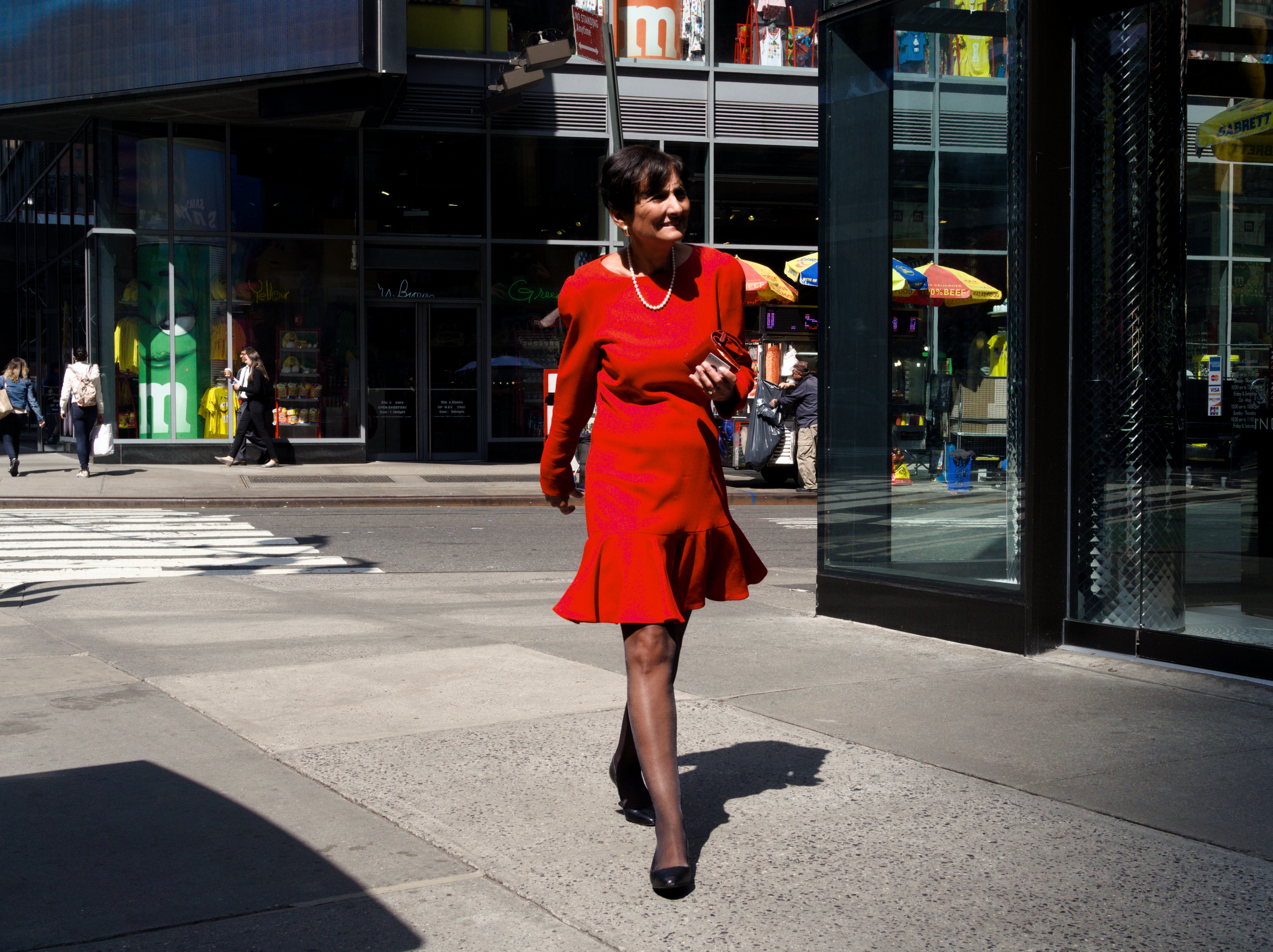 Woman in a red dress against a dark urban background.