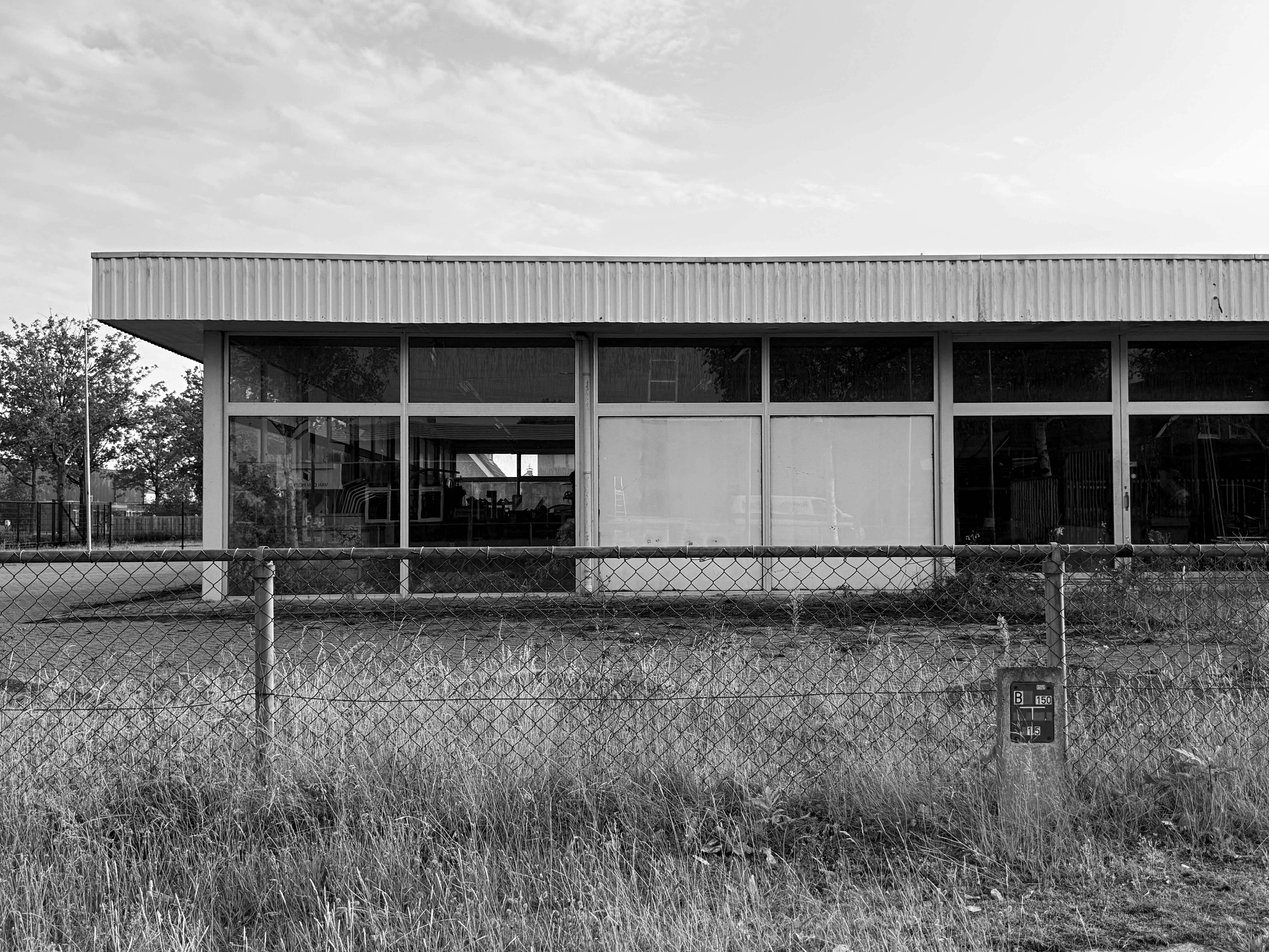Empty building behind a fence with a wide sky in black and white.